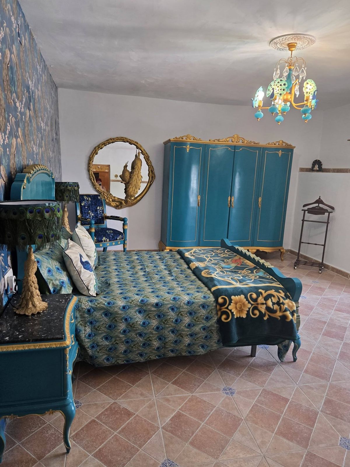 Peacock room with teal wardrobe, gold trim and peacock chandelier